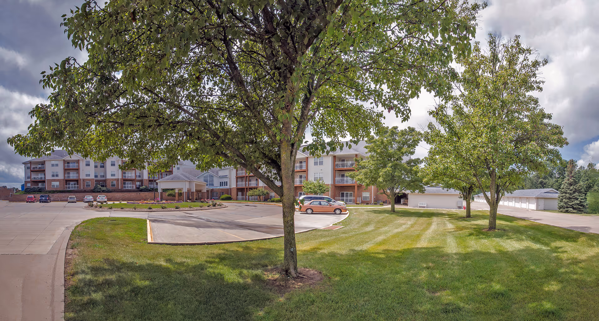 Exterior view of Pennsylvania Place senior living facility with lawn, trees, and parking.