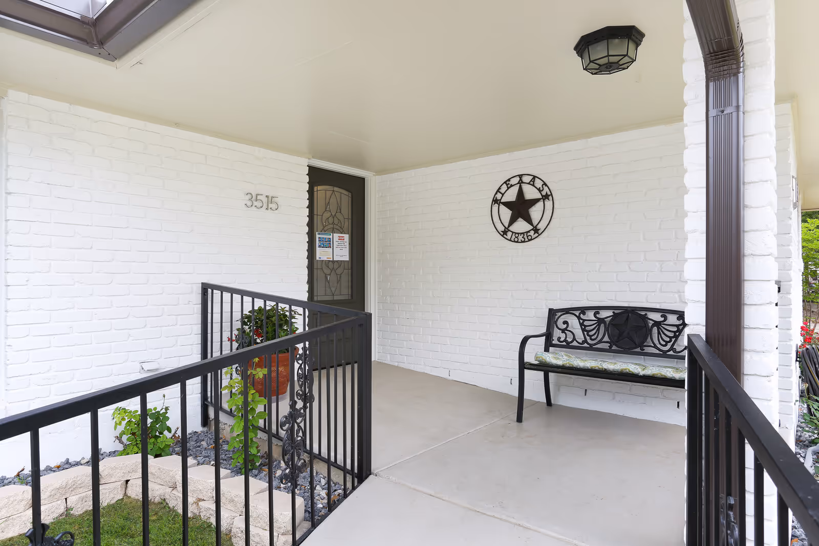 White brick entrance porch of Marinas Assisted Living with a bench and decorative star wall plaque.