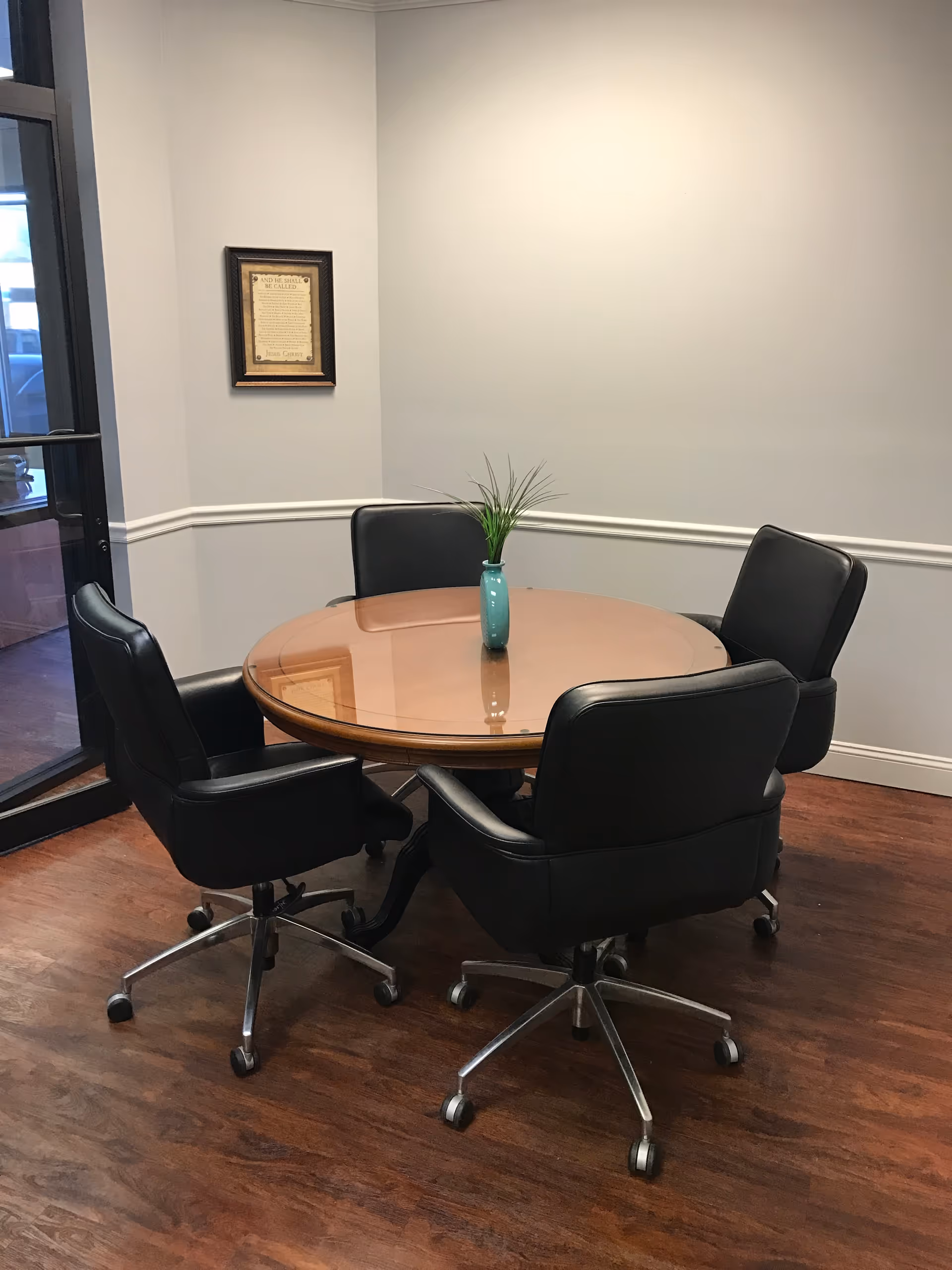 Round dining table with four black chairs and a turquoise vase.