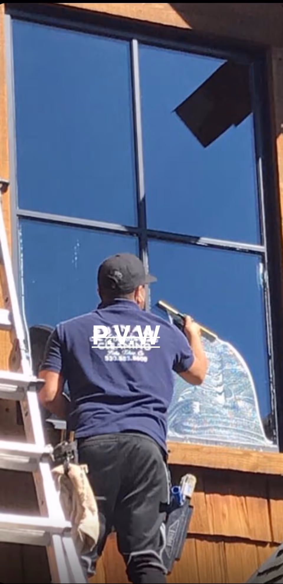 A window cleaner on a ladder works on a building's exterior.