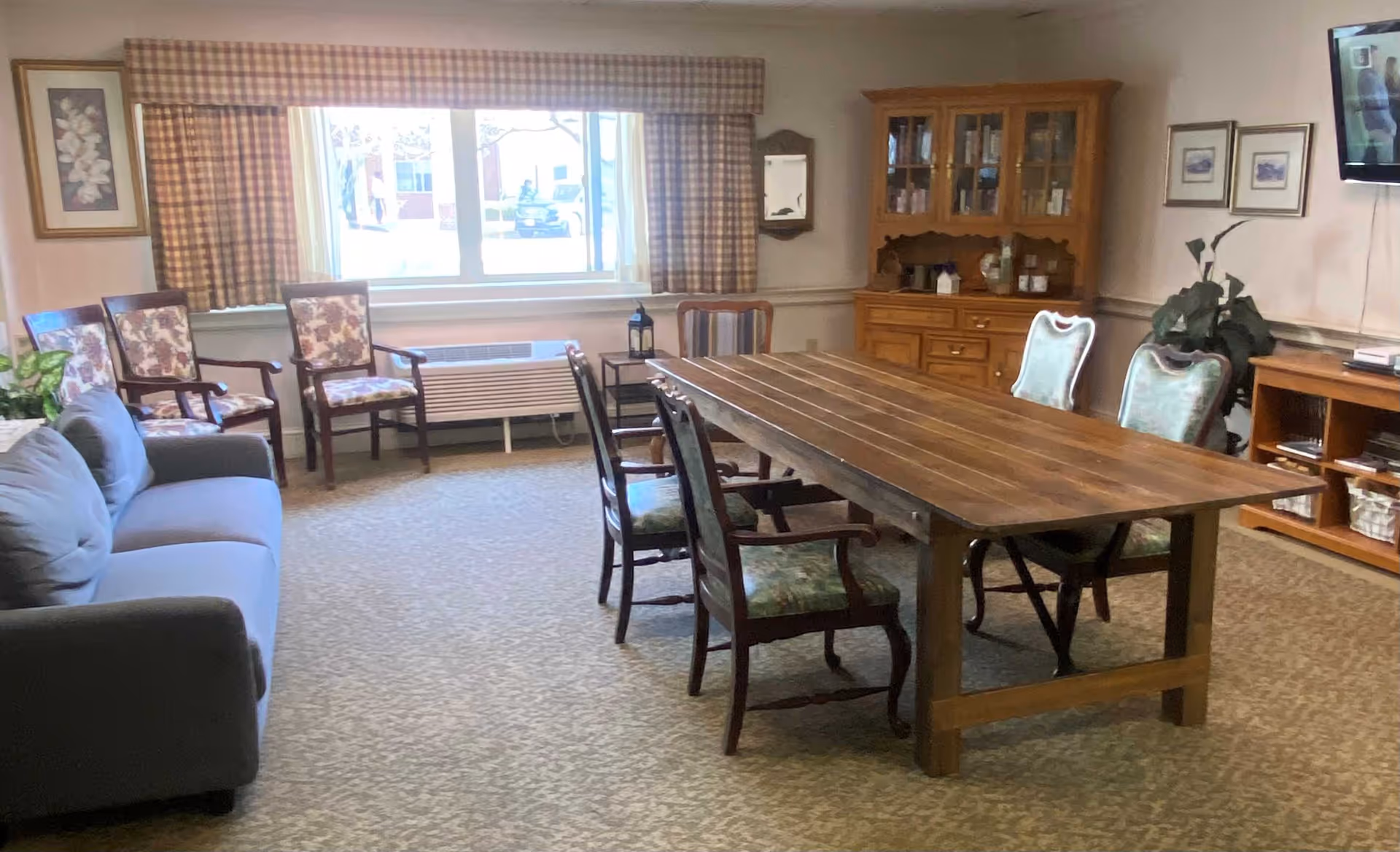 A senior living common area with a long wooden dining table and chairs.