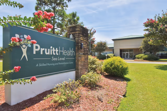 Exterior view of PruittHealth Hospice sign with landscaping and building entrance.