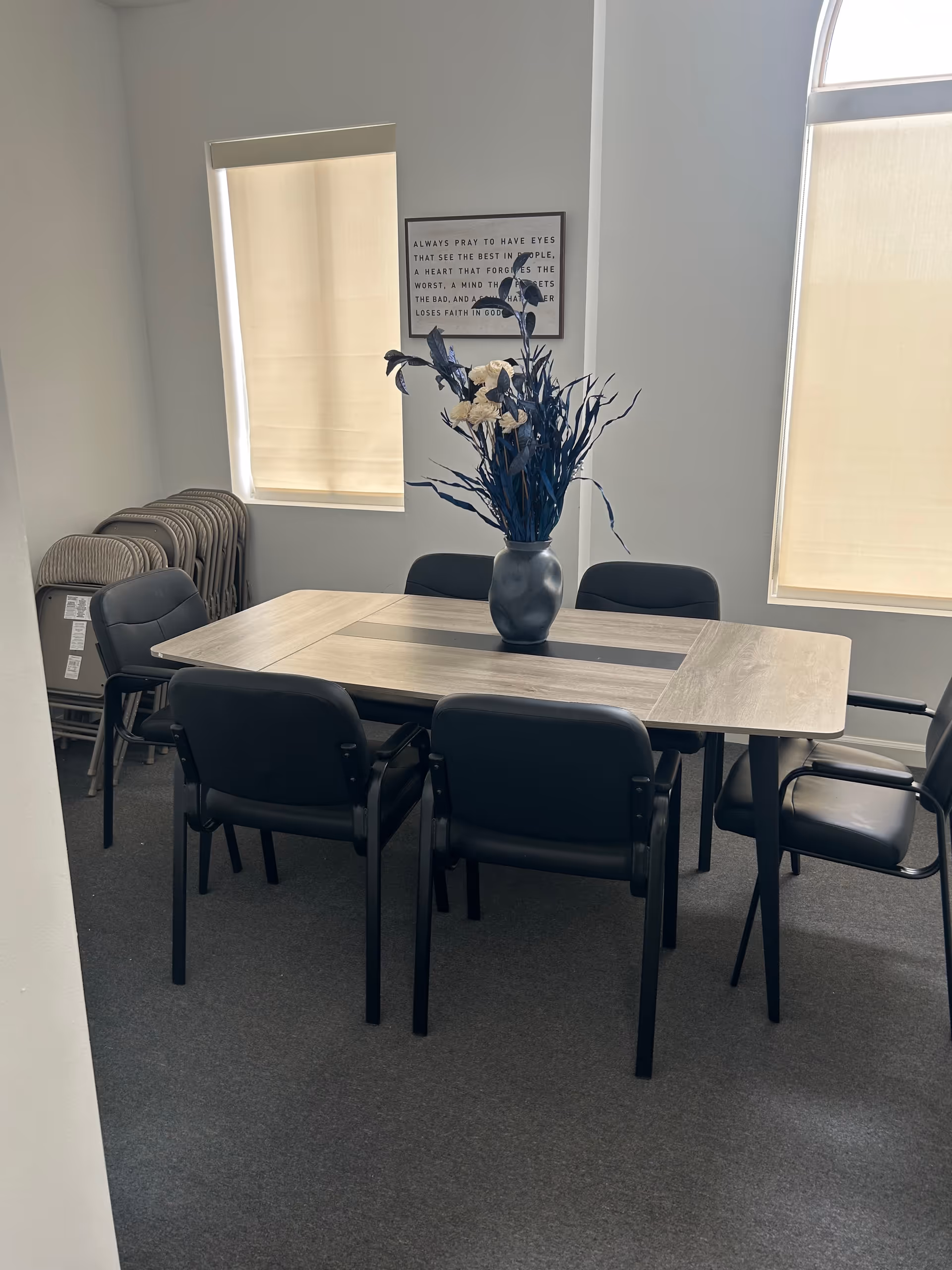 A rectangular dining table with six chairs and a centerpiece vase sits in a dining room.