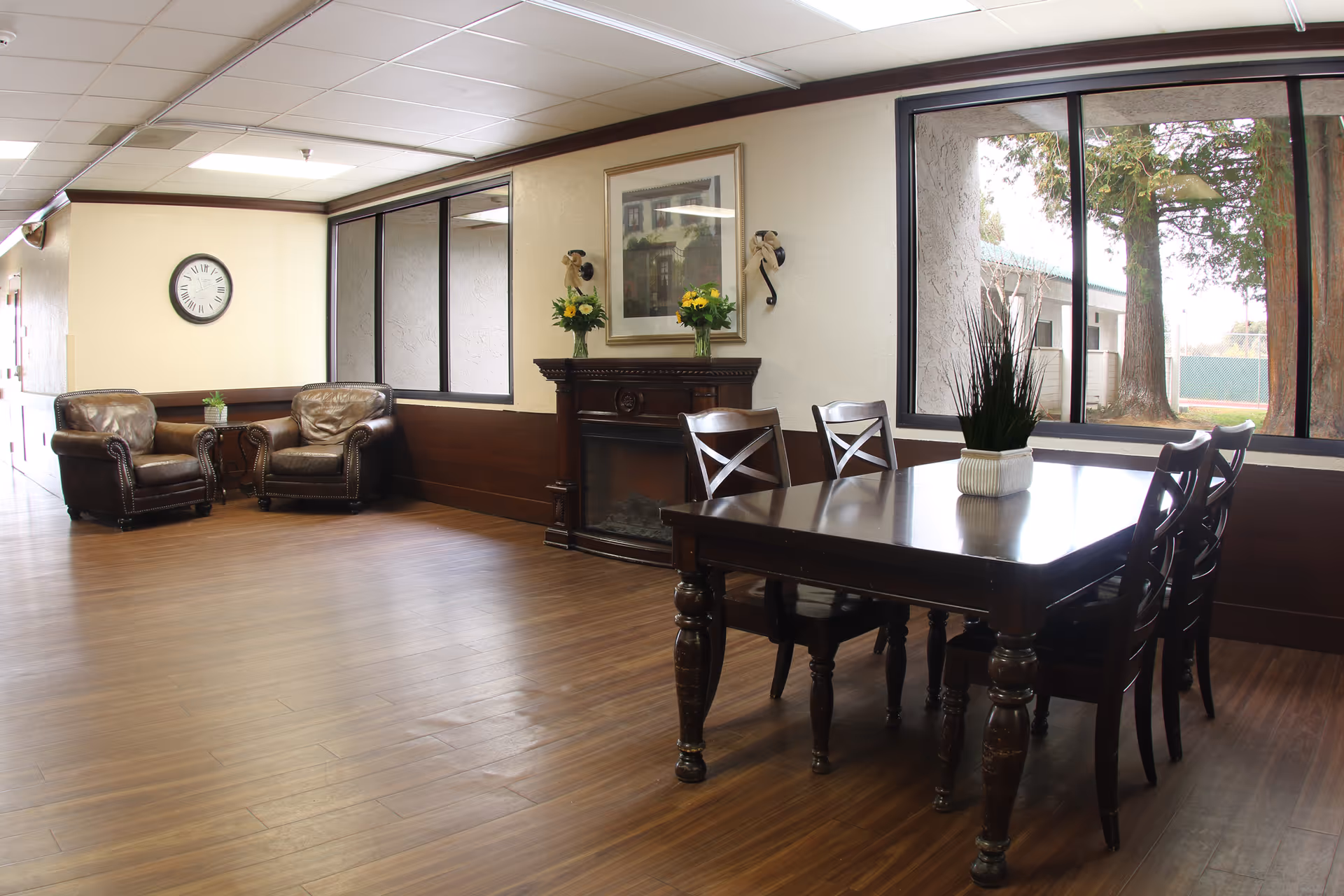 Spacious common area with a dark wooden dining table, leather chairs, and a fireplace.