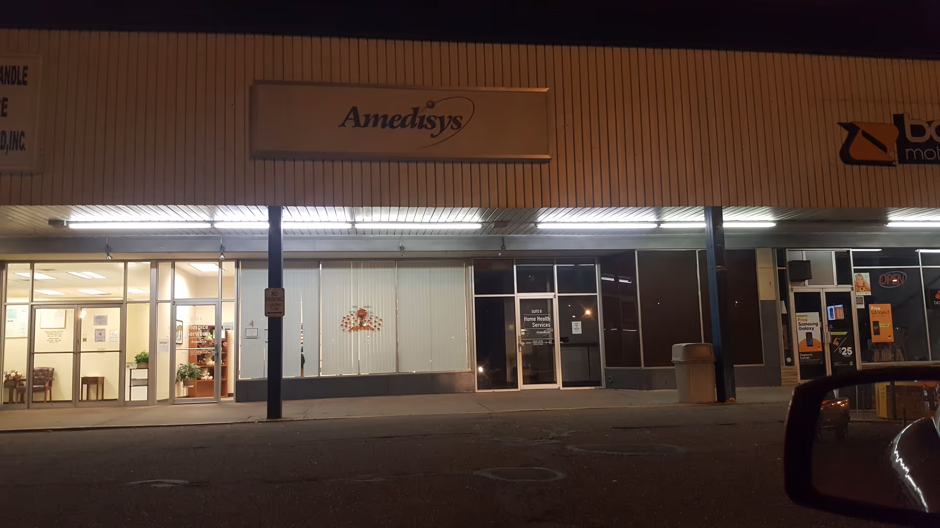 Night exterior of a strip mall with Amedisys signage and Home Health Services entrance.