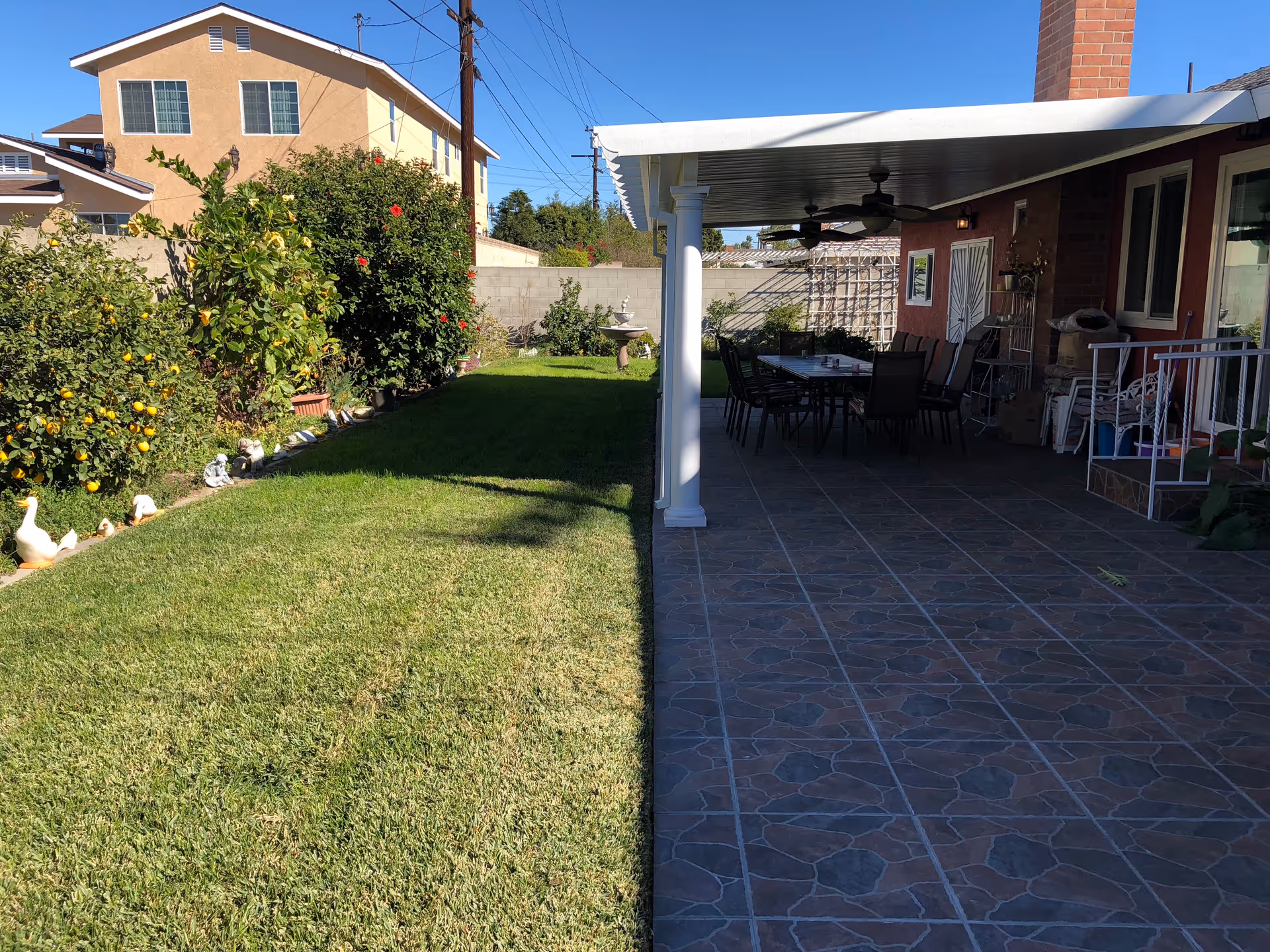 Lush backyard with a spacious lawn and covered patio dining area.