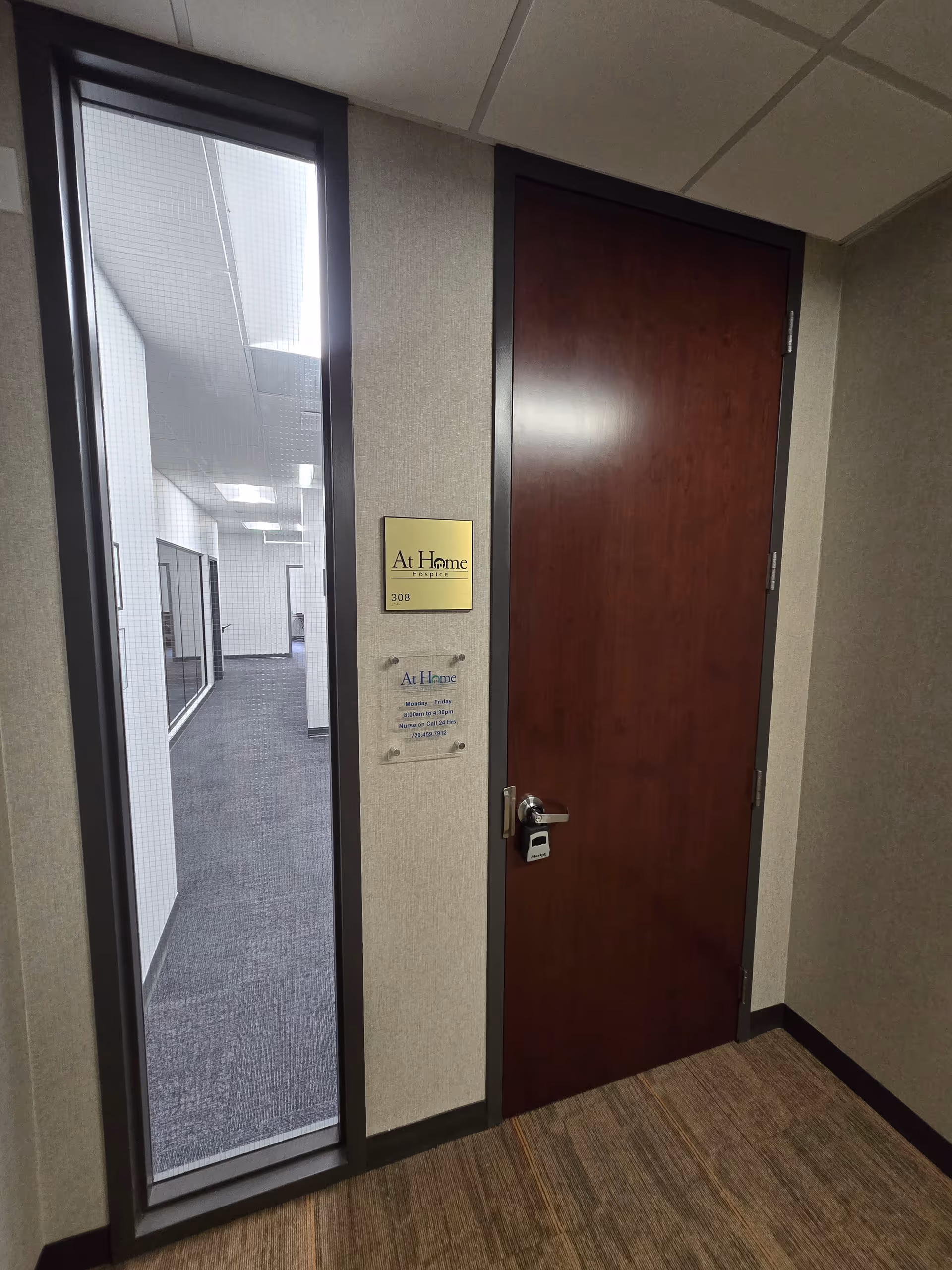 Interior hallway with a dark wooden door and a gold At Home Hospice plaque.