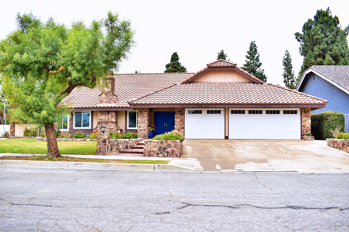 Front view of a single-story house with a two-car garage and manicured lawn.