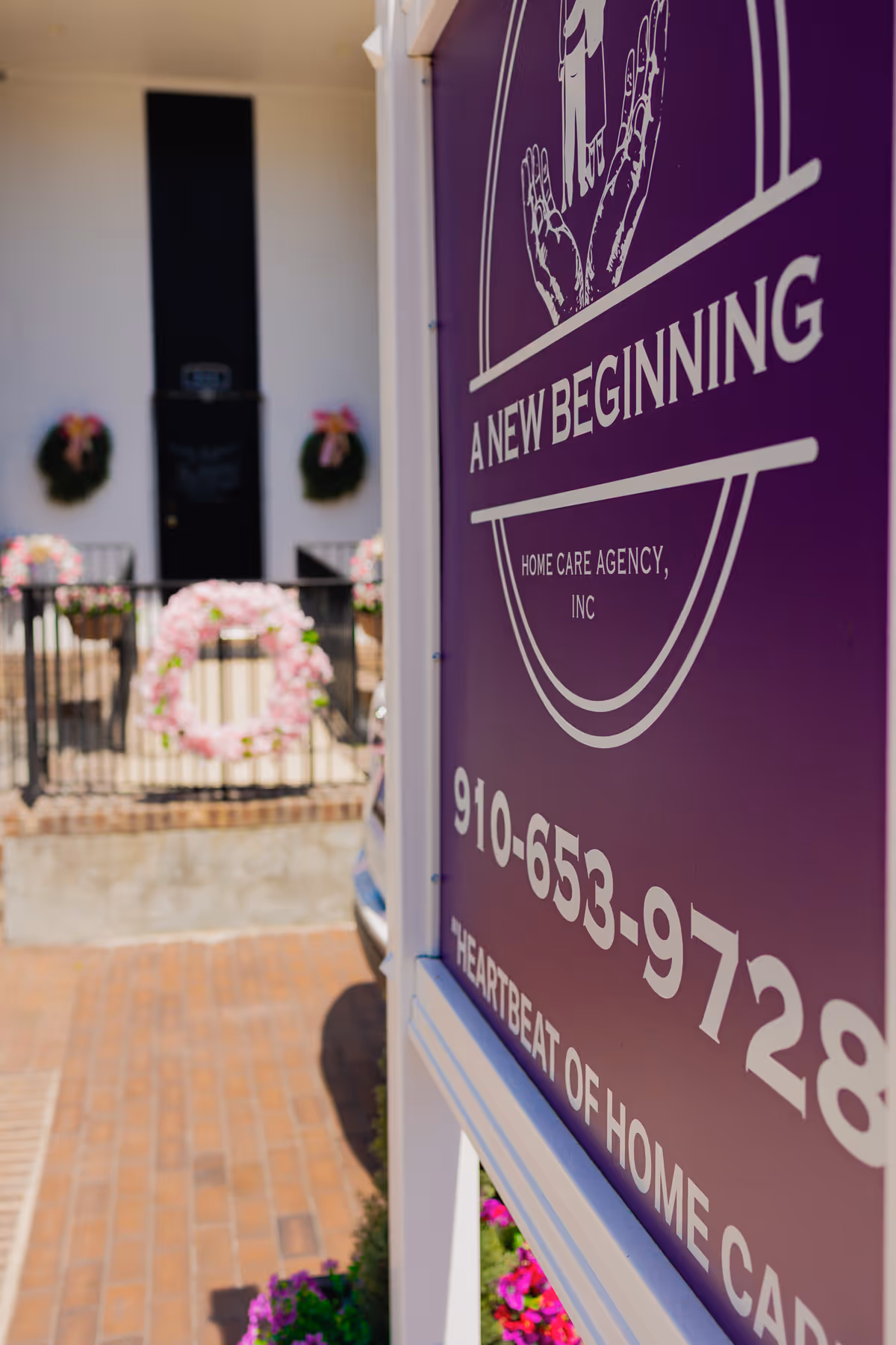 Purple sign for A New Beginning Home Care Agency beside the building entrance and wreaths