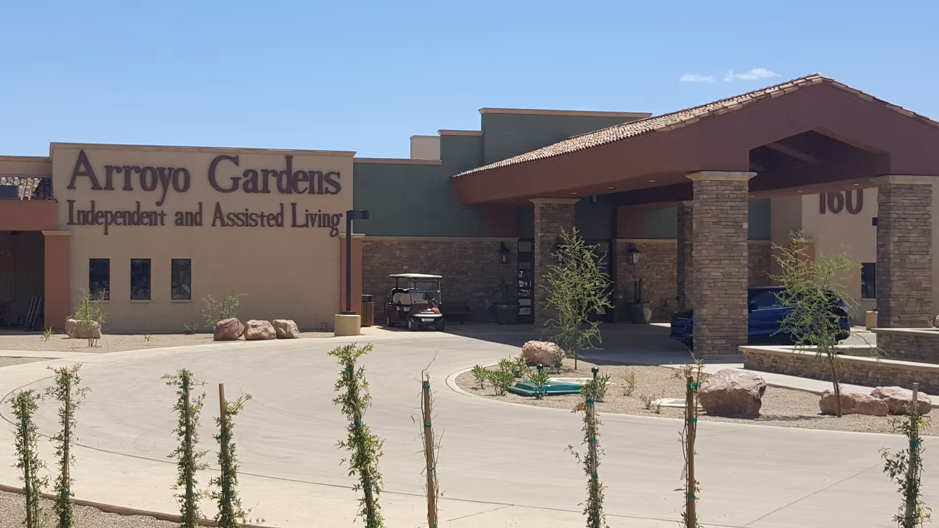 Exterior view of Arroyo Gardens senior living facility with entrance and signage