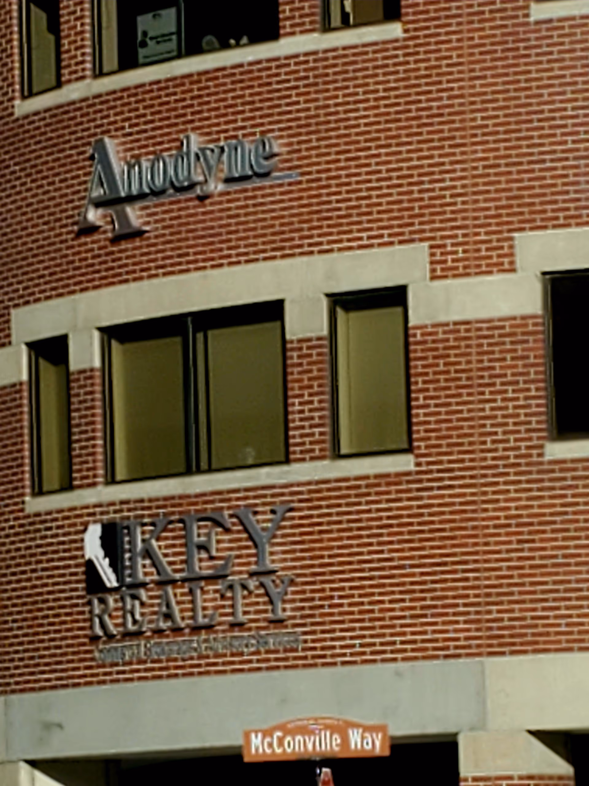 Brick building exterior with Anodyne and Key Realty signage along McConville Way.