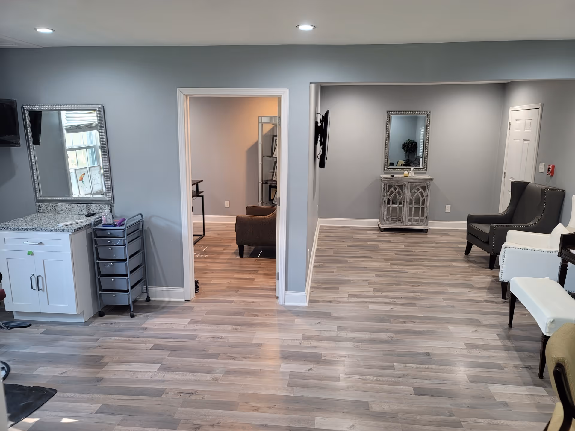 Interior of a senior living lounge with gray walls, light wood flooring, and seating.