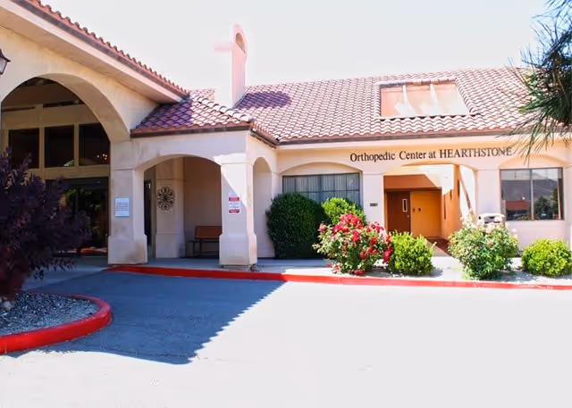 Entrance and front facade of the Hearthstone of Northern Nevada building with an arched portico, tiled roof, and landscaped flower beds.