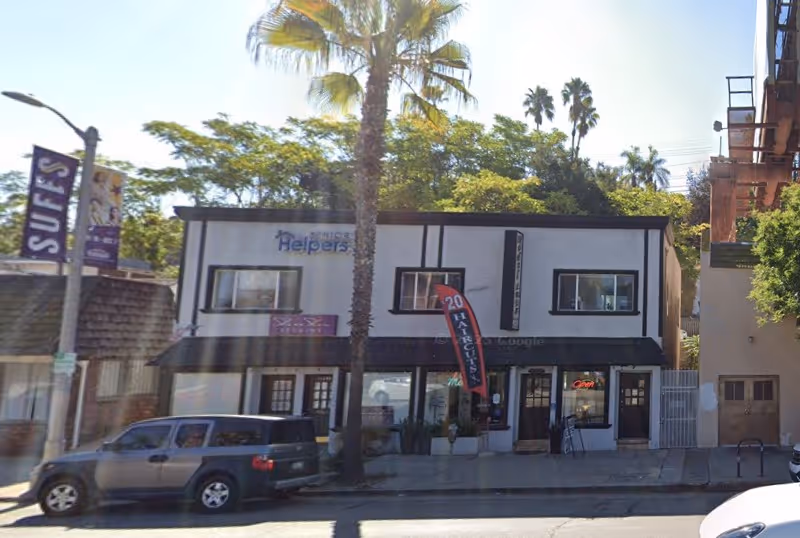 Two-story storefront building with 'Helpers' sign on a sunny street.