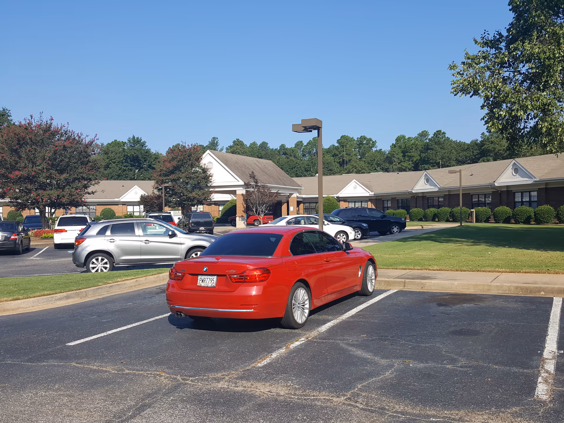Exterior view of a senior living facility with cars parked in front.