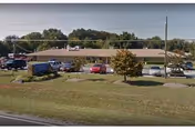 A single-story senior living facility exterior with a parking lot and trees.