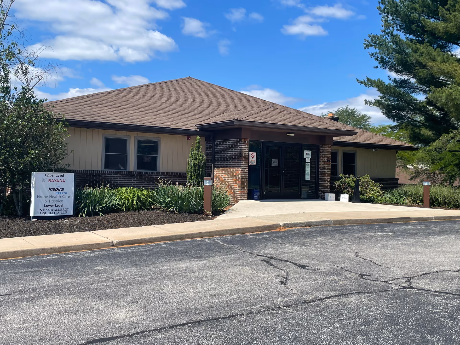 Front view of a single-story hospice facility entrance with brick facade and sign.