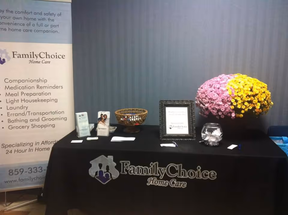 Indoor information table with FamilyChoice Home Care banner, framed sign, and flowers