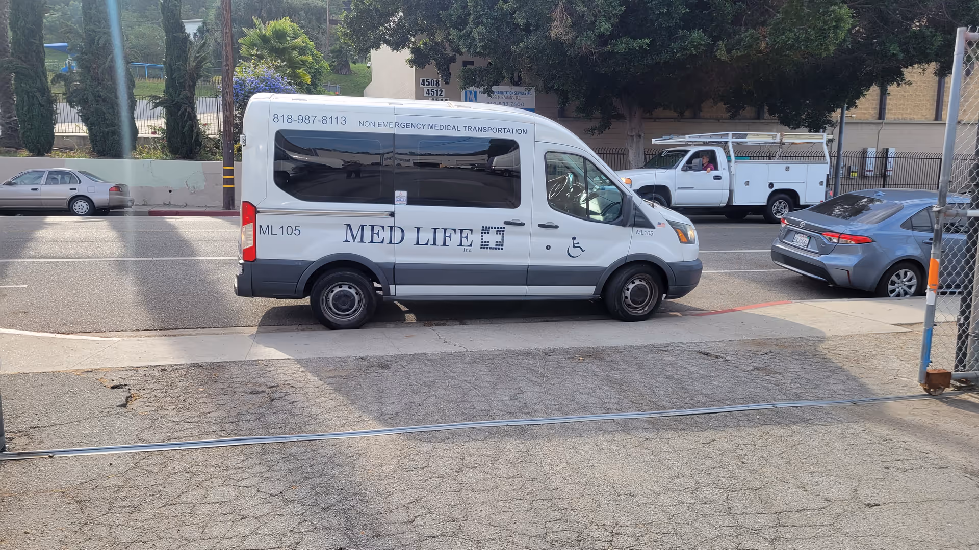 White Med Life Home Health transport van on street with parked cars