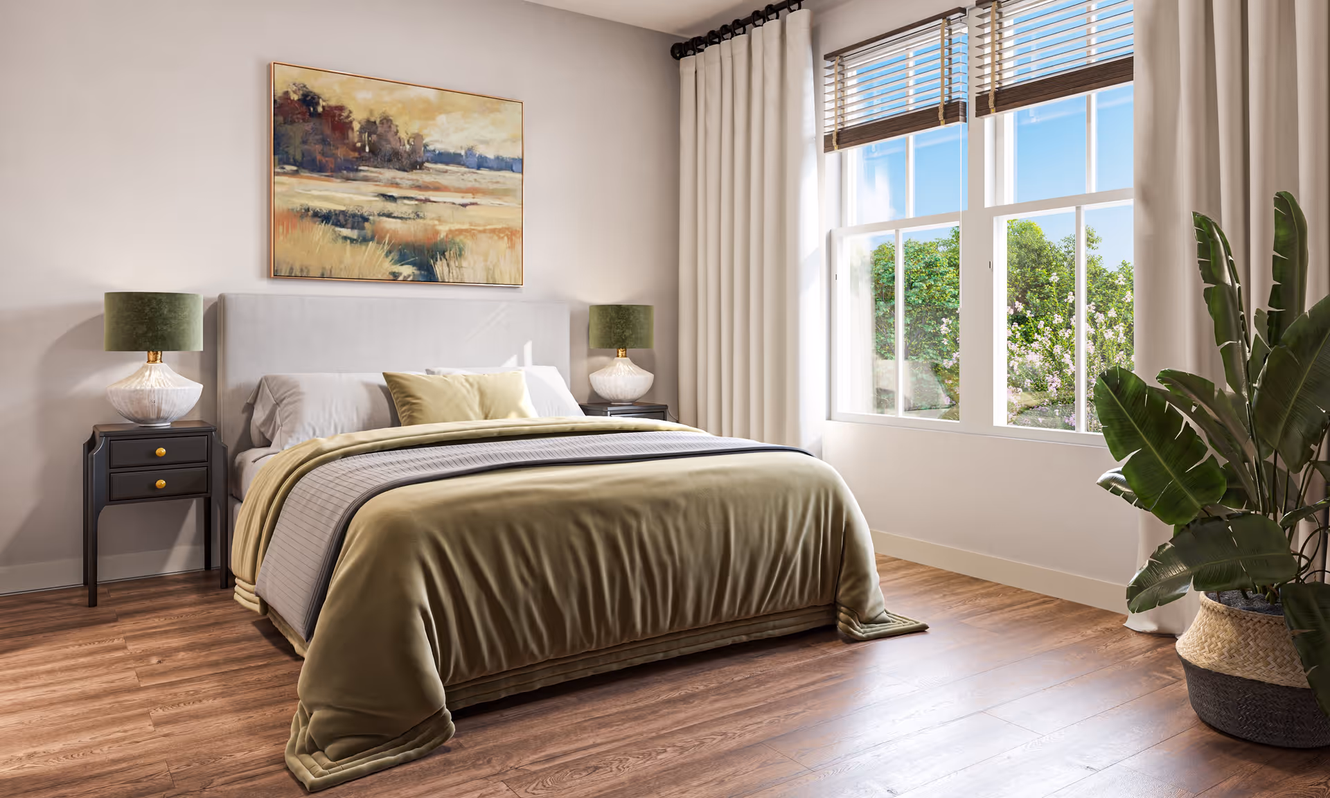 A bright bedroom with a large bed covered in olive green and gray bedding, flanked by two black nightstands each with a white and green lamp. A large window with white curtains and wooden blinds lets in natural light, showing greenery outside. A large leafy plant in a woven basket sits in the corner, and a landscape painting hangs above the bed on a light-colored wall. The floor is wood.