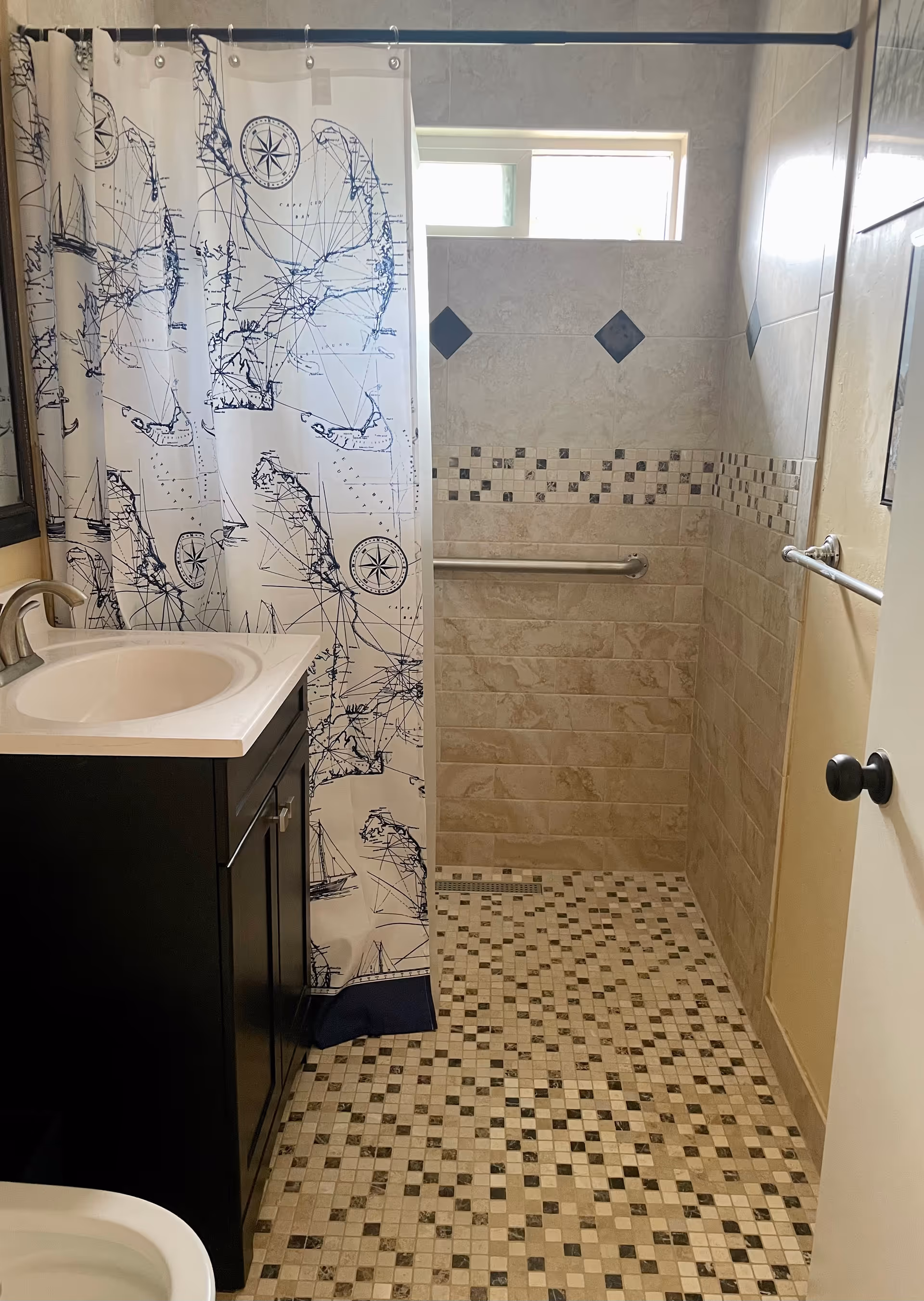 Small bathroom with a sink vanity, shower, grab bars, and tiled walls.