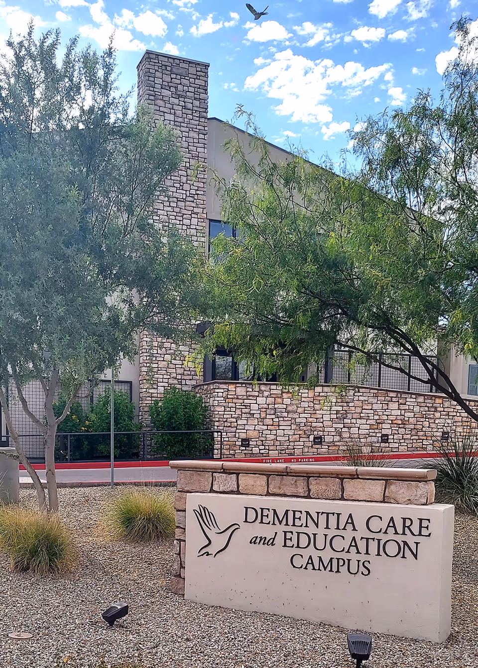 Stone building exterior with a sign reading Dementia Care and Education Campus in front.