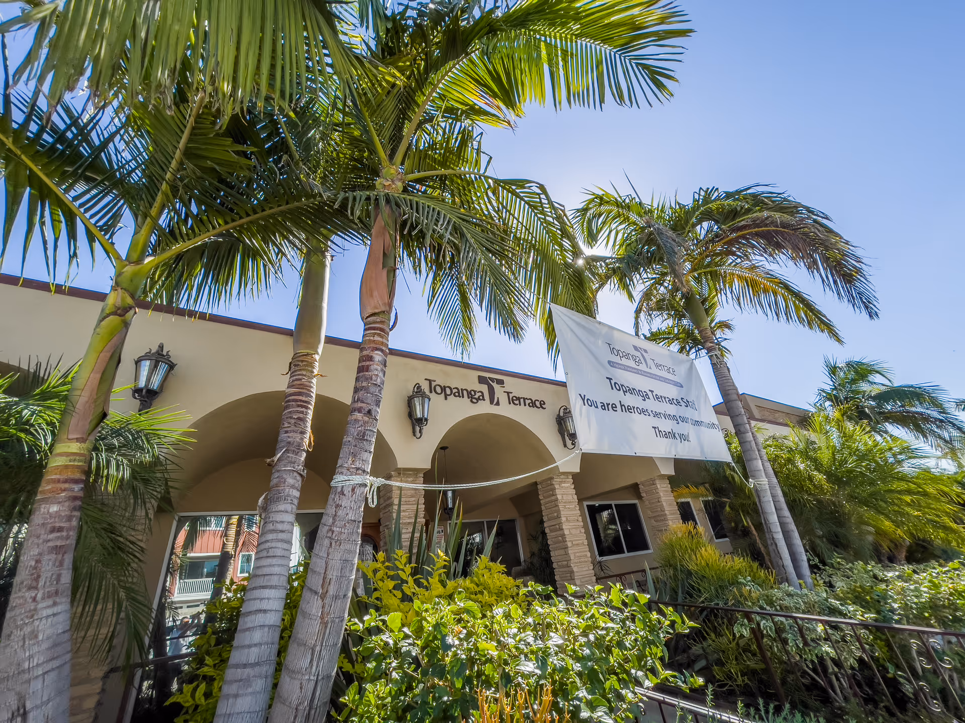 Facade of Topanga Terrace Rehabilitation front with palm trees and a banner.