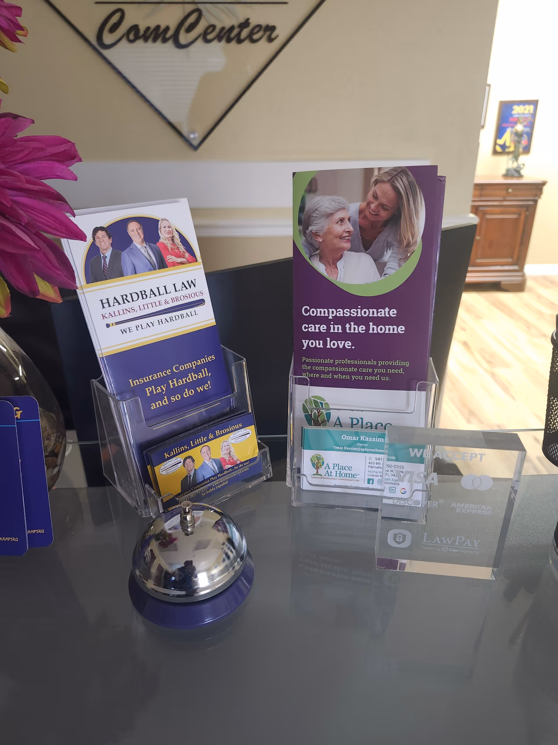 Reception desk with brochures, a bell, and flowers at A Place At Home Palmetto