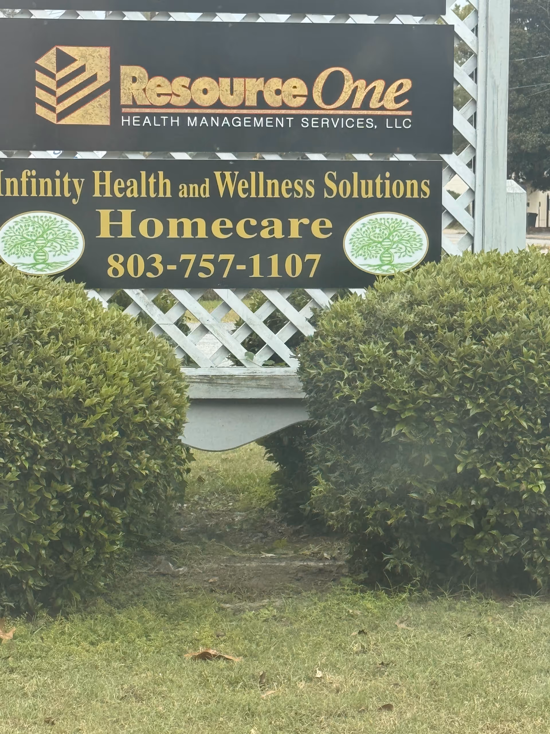 Exterior signs for ResourceOne and Infinity Health and Wellness Solutions with hedges.