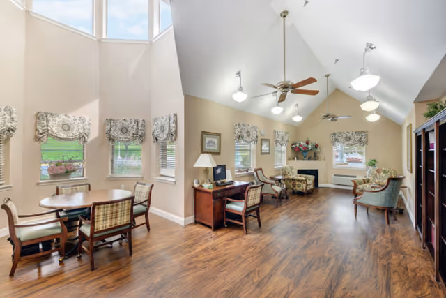 Bright common lounge in a senior living facility with seating groups and wood flooring.