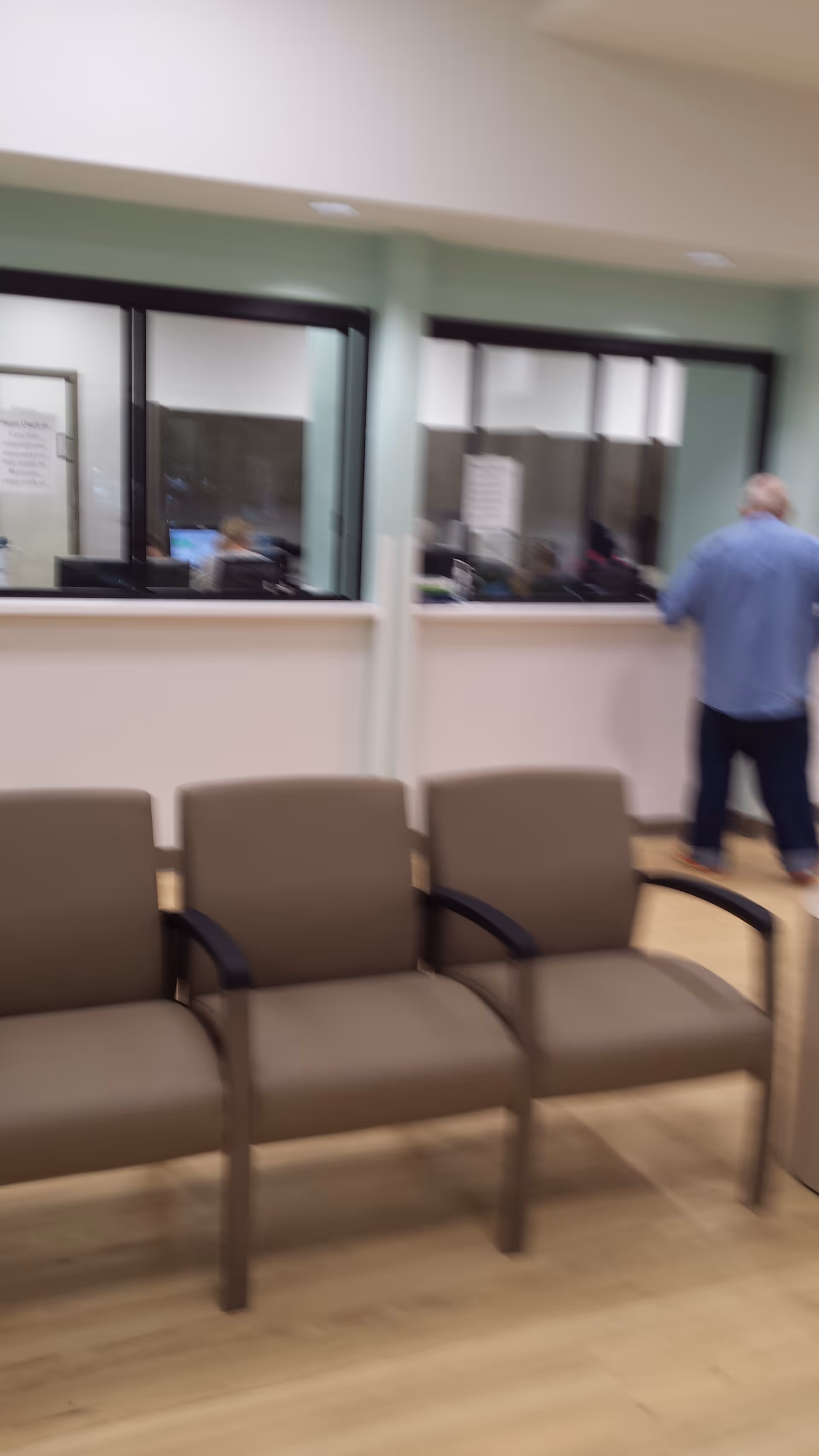 Blurred indoor waiting area with beige chairs and a reception window behind.