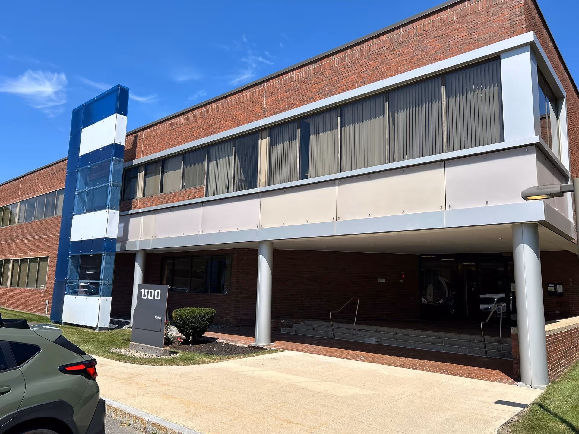 Modern brick senior facility exterior with glass entrance and blue column feature.