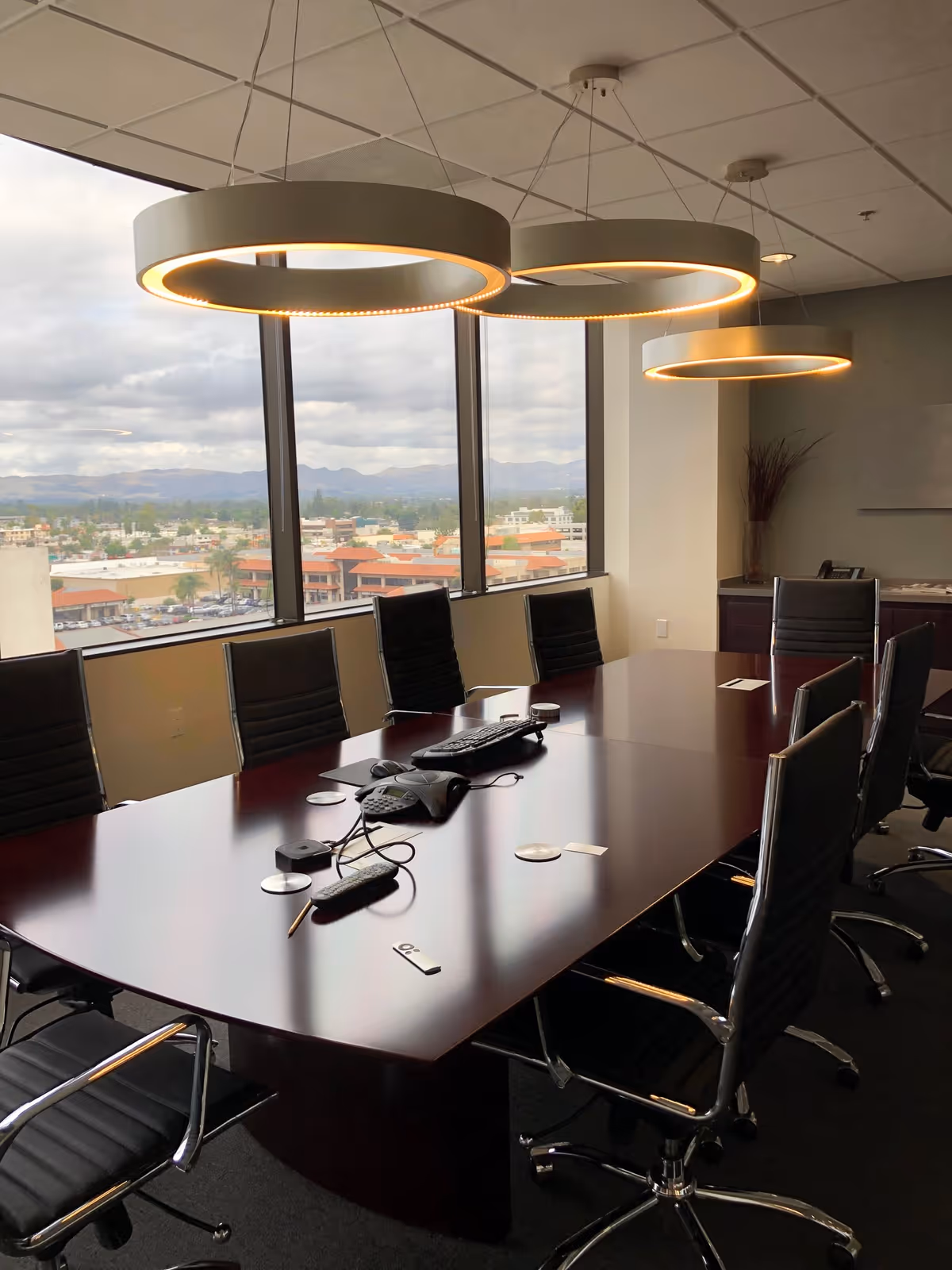 Modern conference room with a large tabletop, black chairs, and panoramic window view.