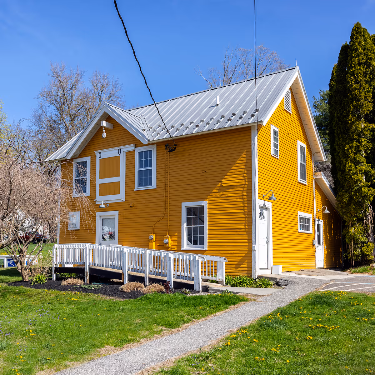 Bright yellow building with white trim, a ramp, and a blue sky.