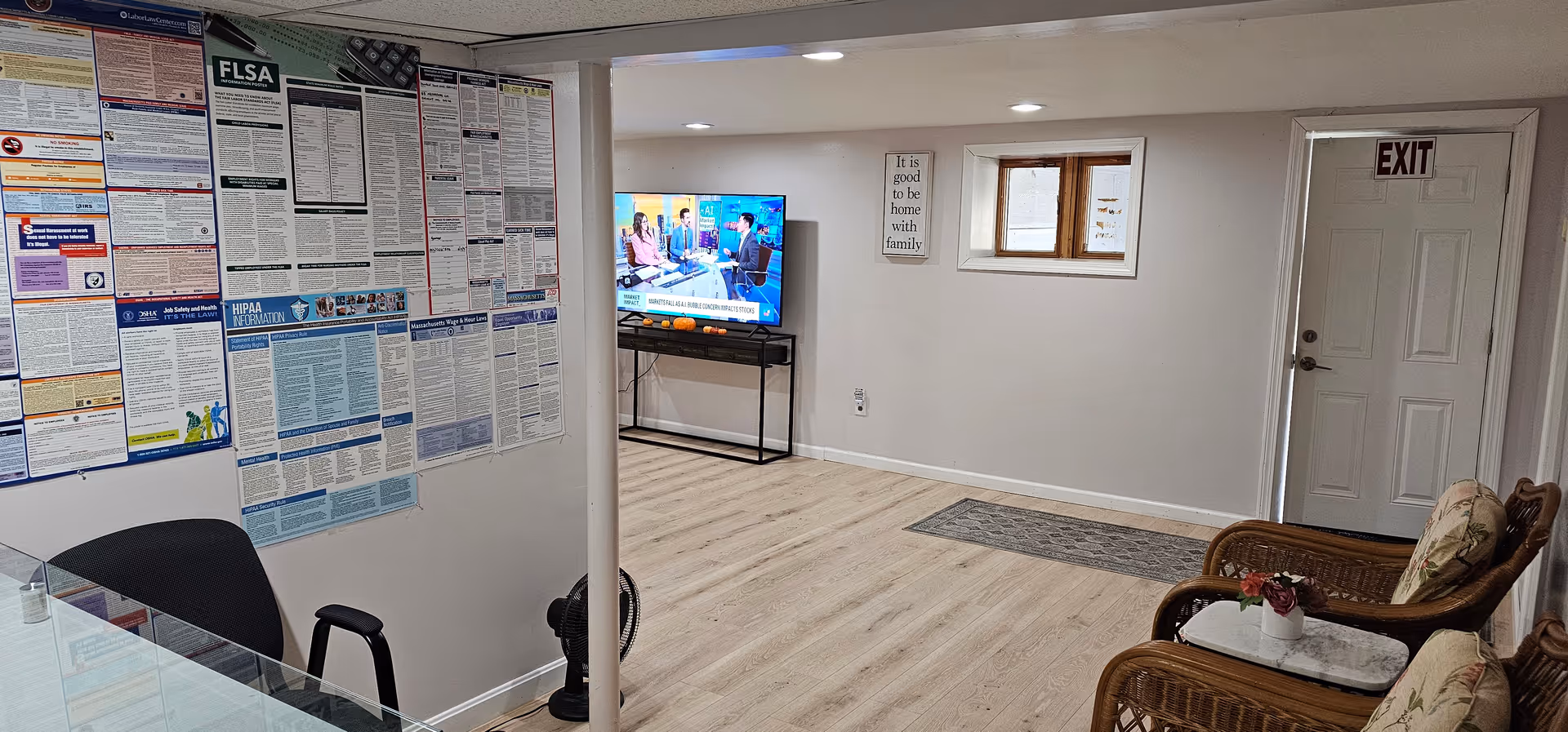 Interior living area with posters on the wall, a TV on a stand, and wicker seating.