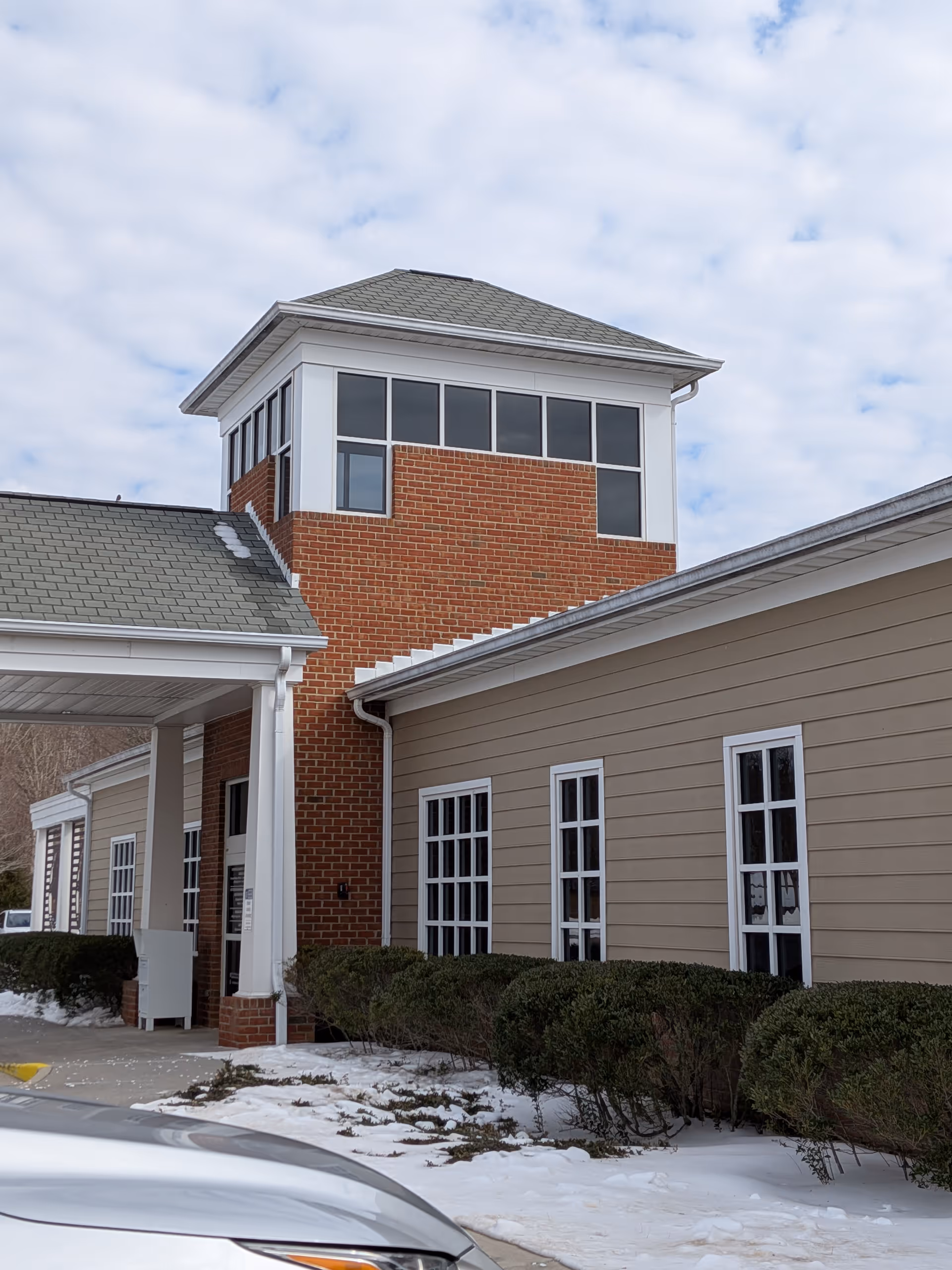 Exterior view of Carilion Clinic Home Care Bedford building with brick tower and snow.