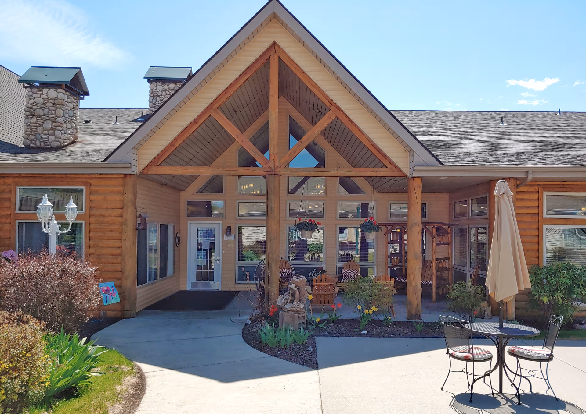 Front entrance of Guardian Angel Homes Post Falls with wooden beams, glass doors, and outdoor seating.