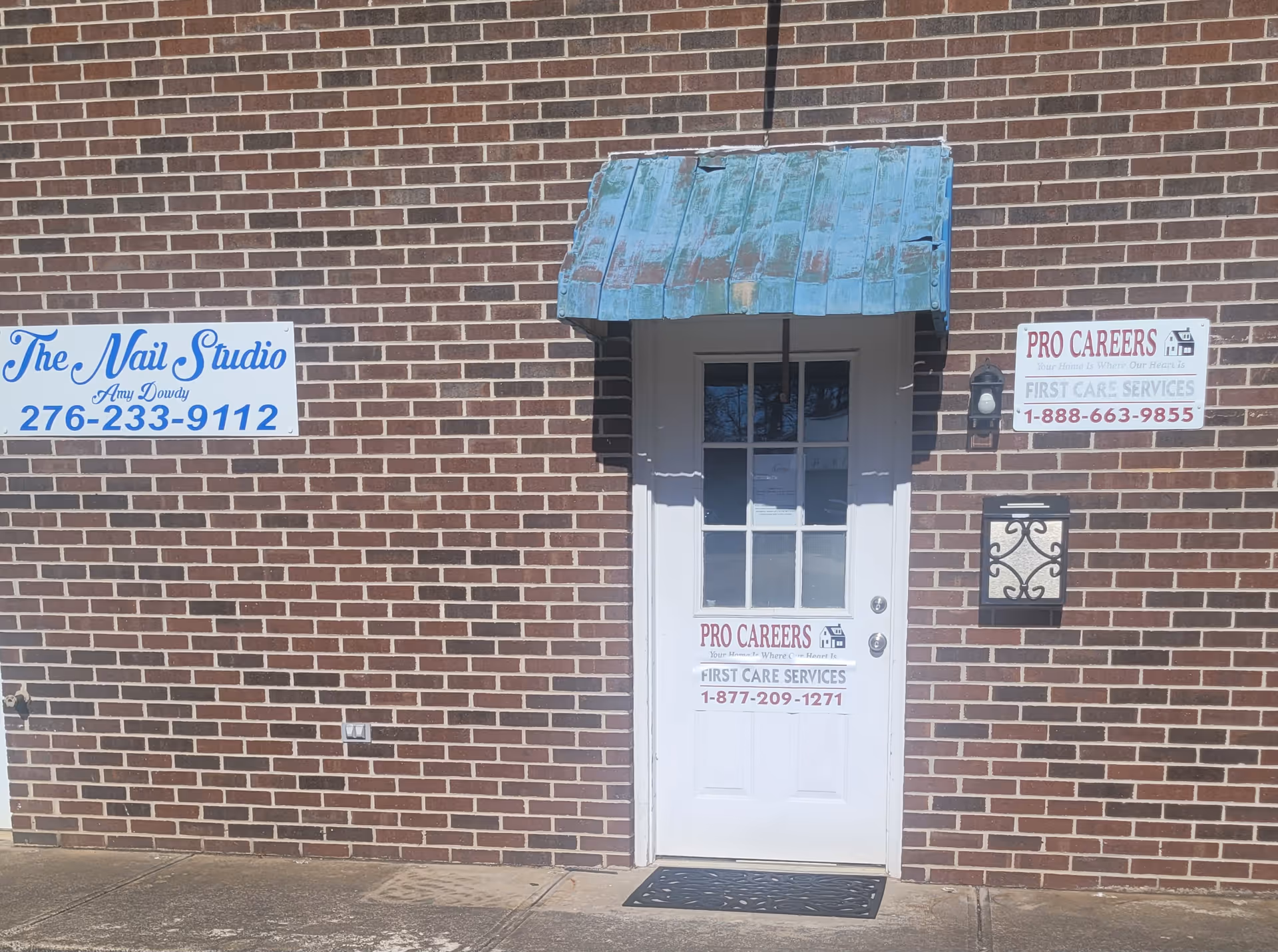 Brick exterior wall with a white door and Pro Careers signs under a blue awning.