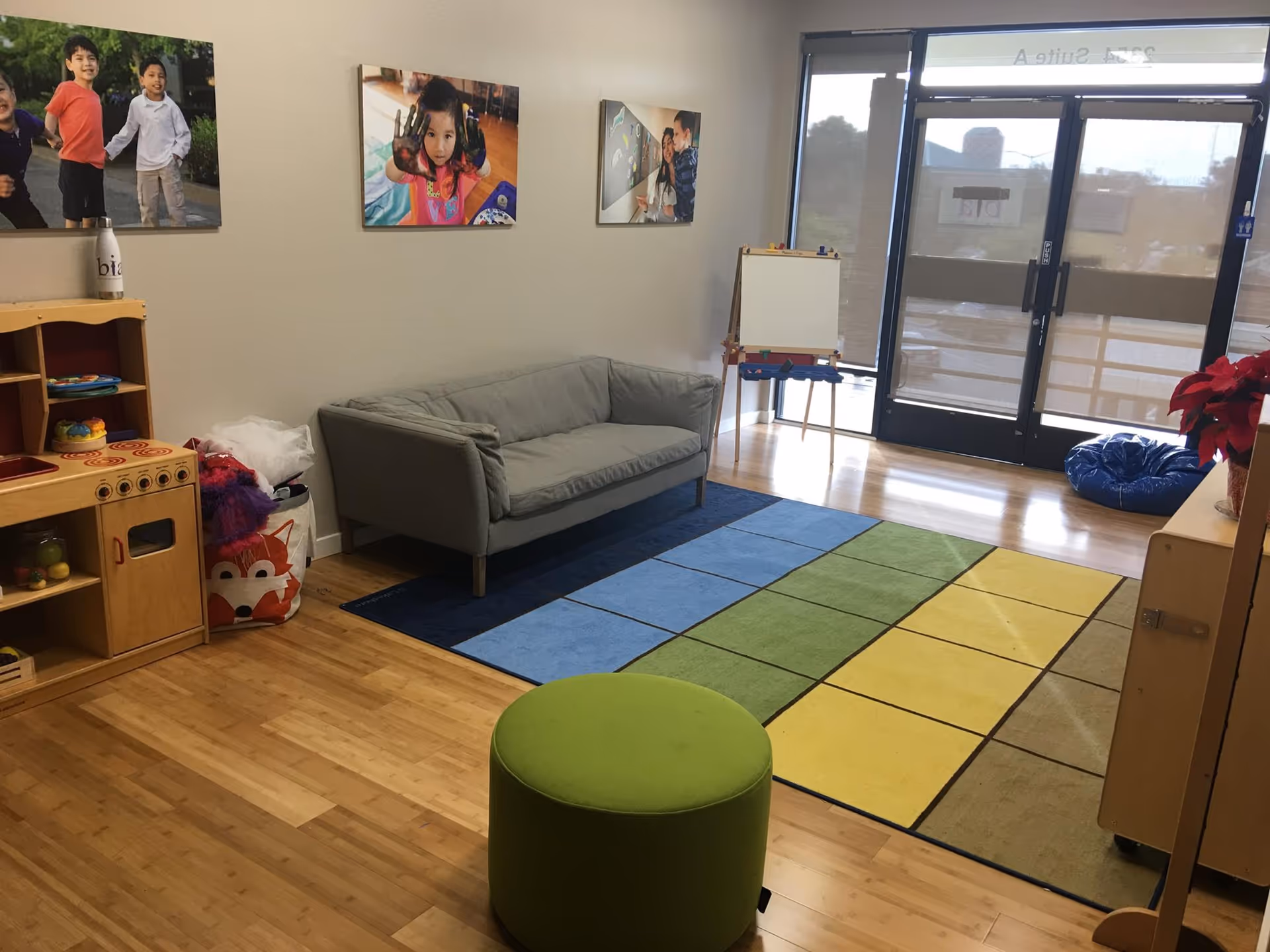 Colorful children's play area with couch, rug, toys, and large glass doors.