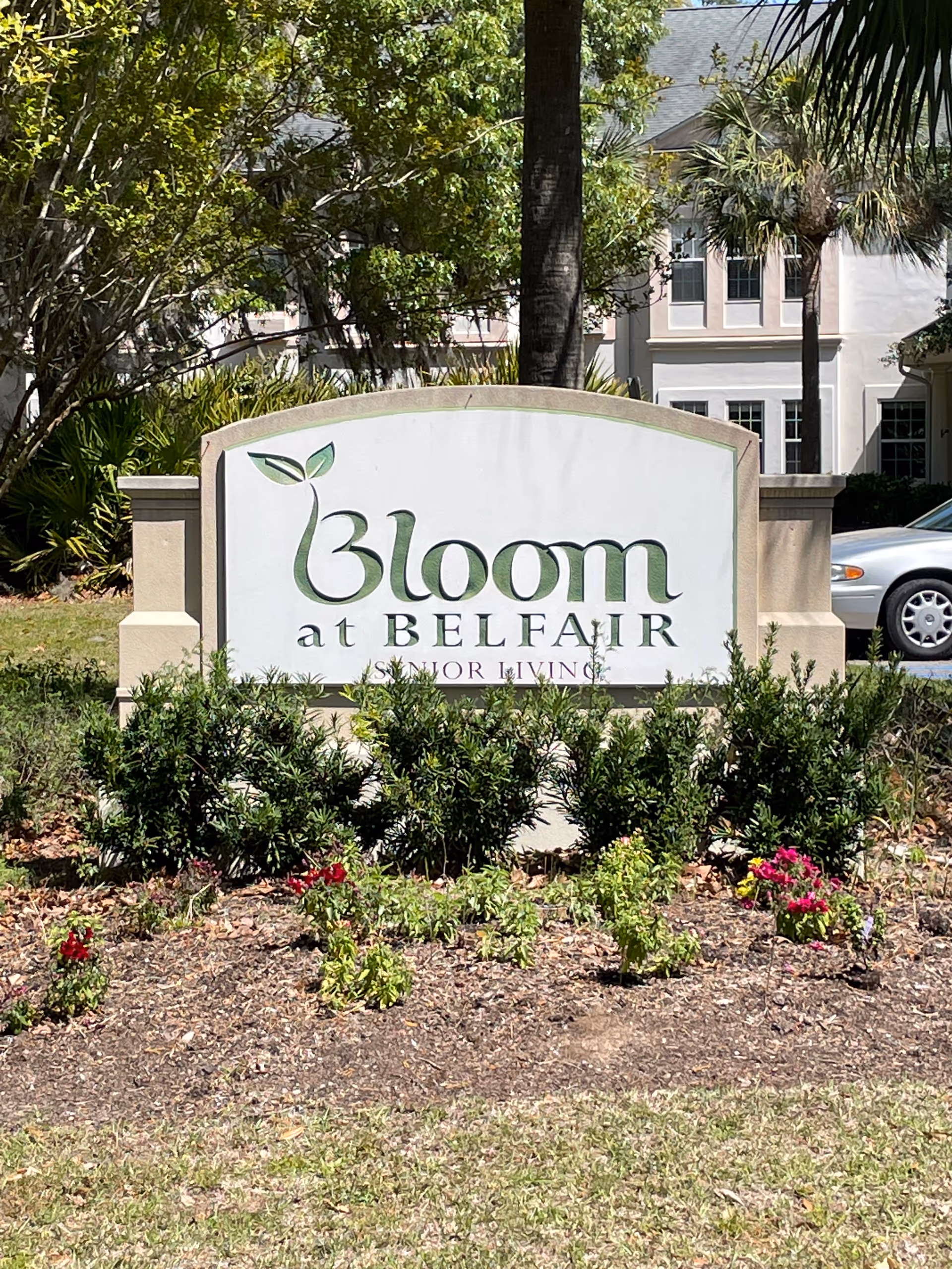 Bloom at Belfair sign in front of a building with landscaping.