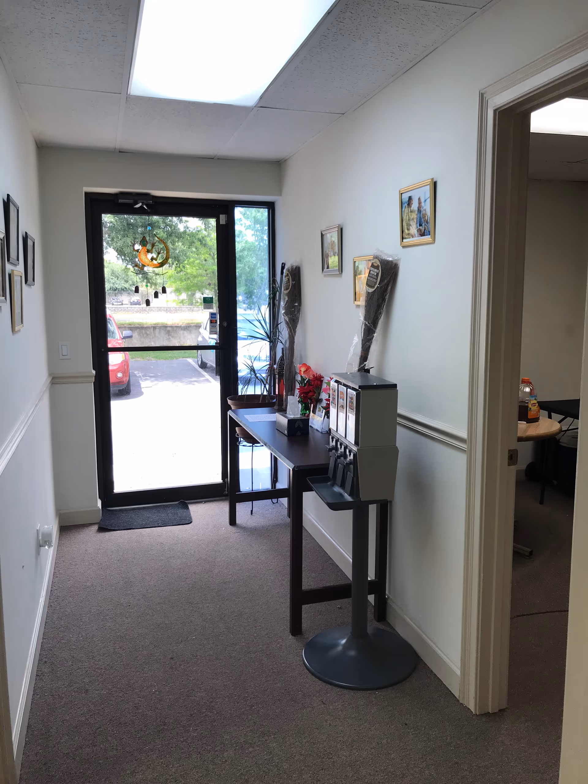 Narrow interior hallway in a senior facility with a beverage station and exit door.