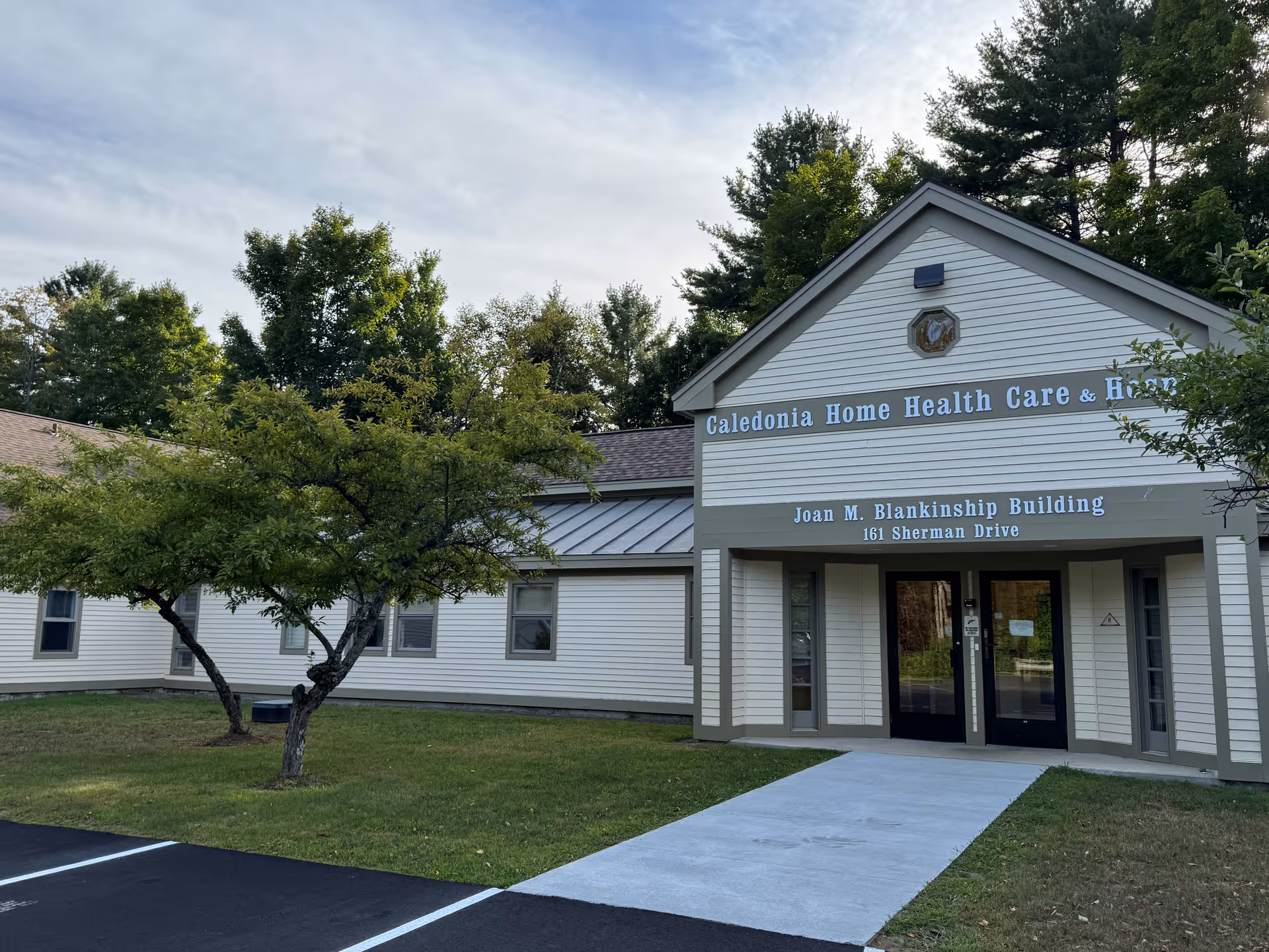 Exterior view of Caledonia Home Health Care & Hospice building with trees.