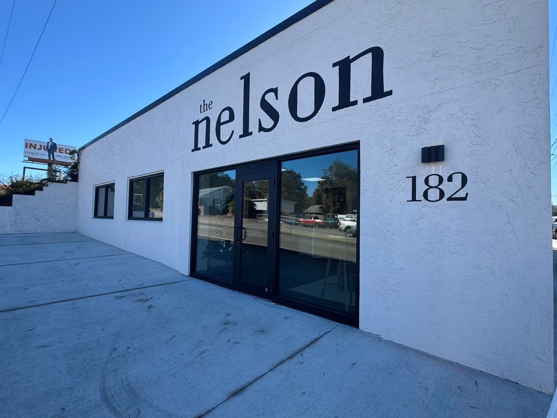 Exterior of The Nelson building with large glass doors and the number 182.