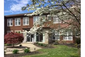 Brick senior living facility facade with entry and landscaped lawn.