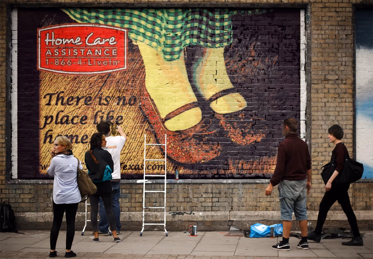 A group of people painting a large mural on a brick building's exterior wall.