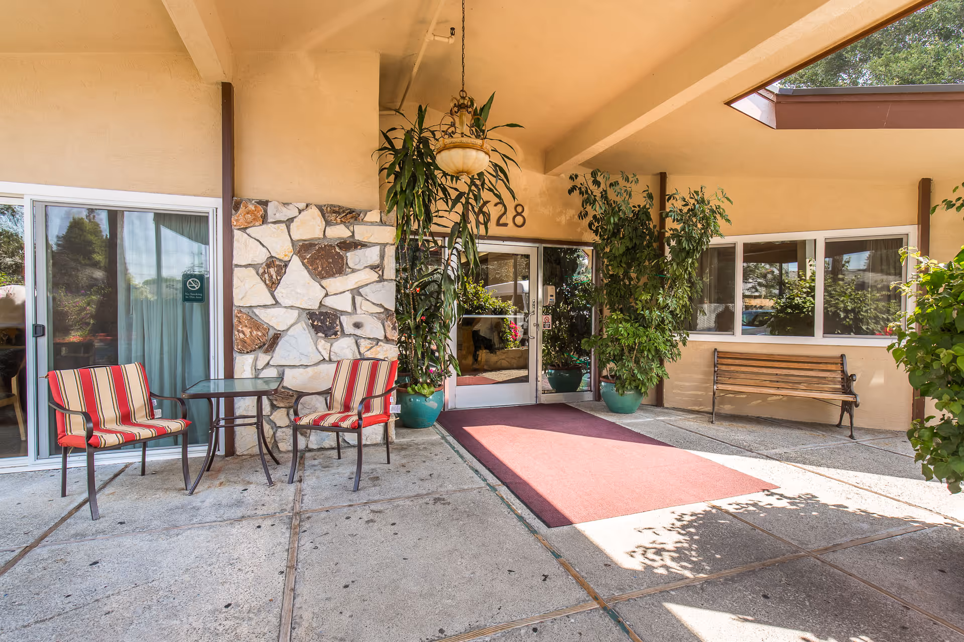 Exterior entrance of Windsor Gardens Care Center of Hayward with red carpet and seating.