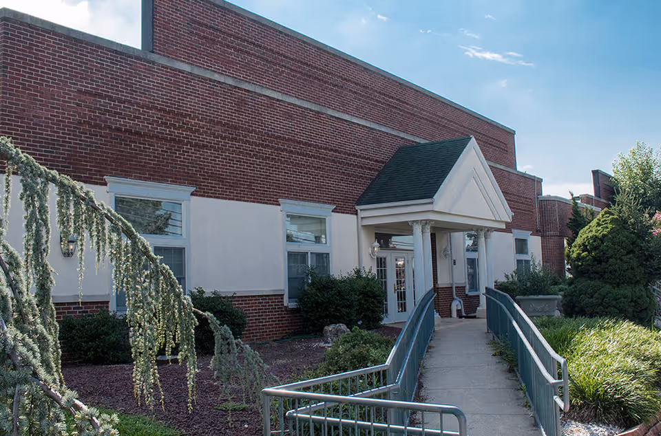 Brick Whitehall Manor exterior with a covered entrance and wheelchair ramp.