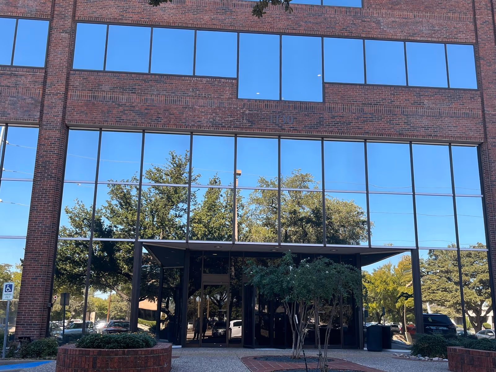 Brick building with large reflective glass windows and a covered entrance canopy.