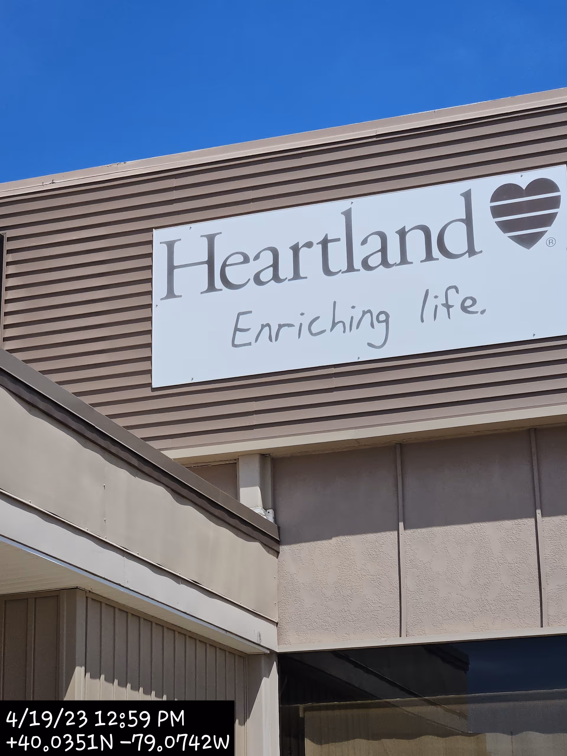 Exterior view of Heartland Hospice building with a large sign and blue sky.