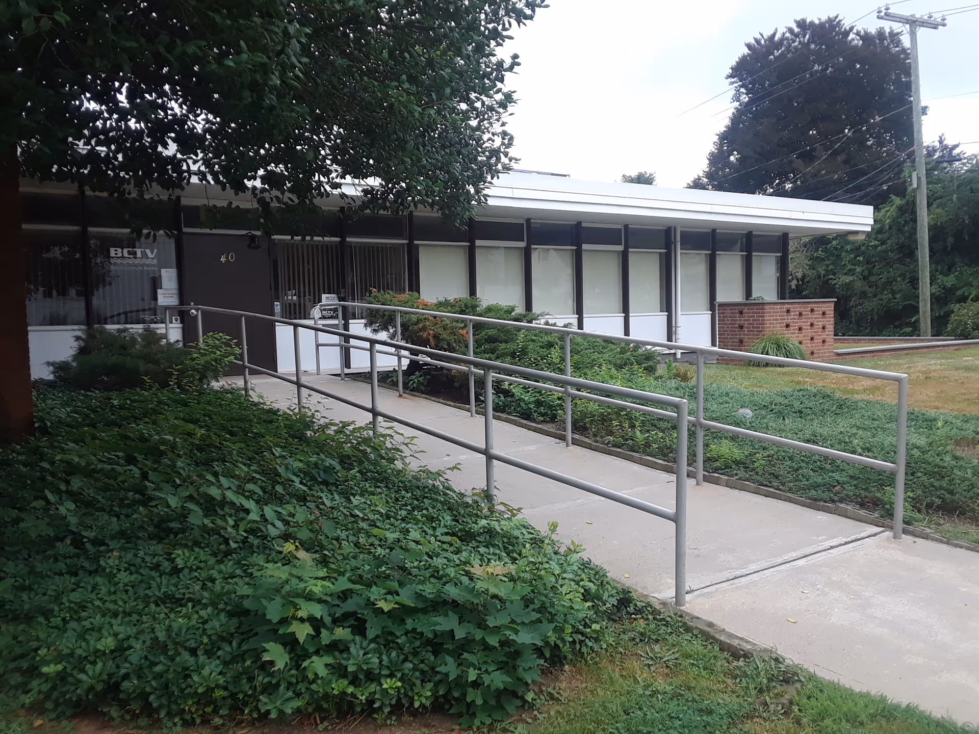Exterior view of a single-story facility with a ramp and greenery